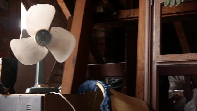 Broken plastic electric fan among other rubbish in the attic