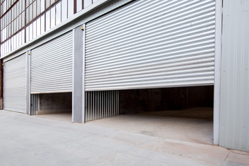 gray steel shutter of an industrial garage with gray concrete porch, side view nobody.