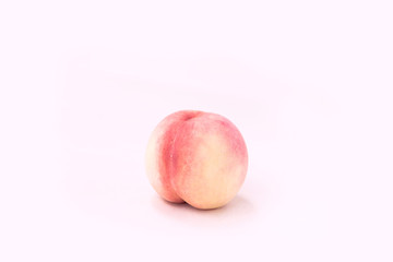 An attractive peach stands alone on a white background.