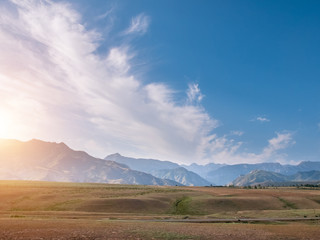Landscape of grassland with cloudy blue sky mountain ranges