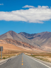 Empty highway traveling towards barren mountains