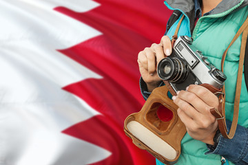 Bahrain photographer concept. Close-up adult woman holding retro camera on national flag background. Adventure and traveler theme.