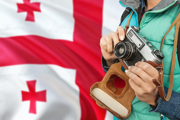 Georgia photographer concept. Close-up adult woman holding retro camera on national flag background. Adventure and traveler theme.