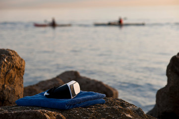 VR headset glasses with classic blue sea, classic blue towel, canoes in the background