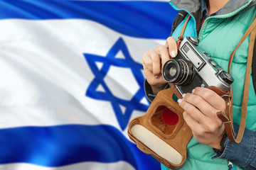 Israel photographer concept. Close-up adult woman holding retro camera on national flag background. Adventure and traveler theme.