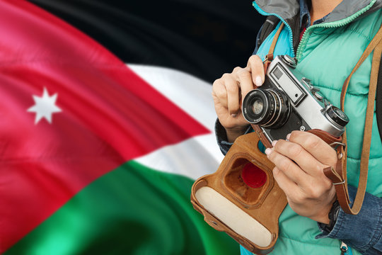 Jordan photographer concept. Close-up adult woman holding retro camera on national flag background. Adventure and traveler theme.