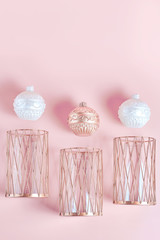 candles in the form of balls of white and copper color. metal candlesticks on pink background. modern home decor. simple flat lay, vertical frame