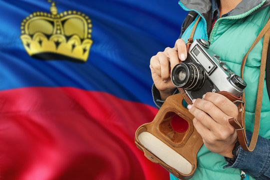Liechtenstein photographer concept. Close-up adult woman holding retro camera on national flag background. Adventure and traveler theme.