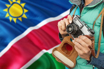 Namibia photographer concept. Close-up adult woman holding retro camera on national flag background. Adventure and traveler theme.