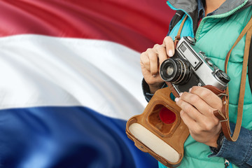 Netherlands photographer concept. Close-up adult woman holding retro camera on national flag background. Adventure and traveler theme.
