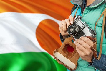 Niger photographer concept. Close-up adult woman holding retro camera on national flag background. Adventure and traveler theme.