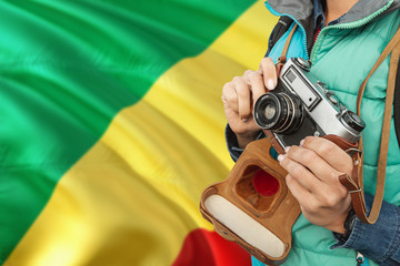 Republic Of The Congo photographer concept. Close-up adult woman holding retro camera on national flag background. Adventure and traveler theme.