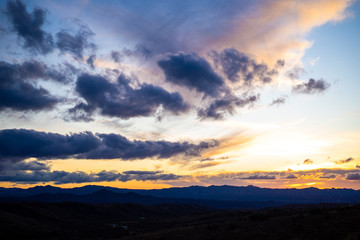 Dramatic blue and yellow clouds over Arizona desert mountains at sunset