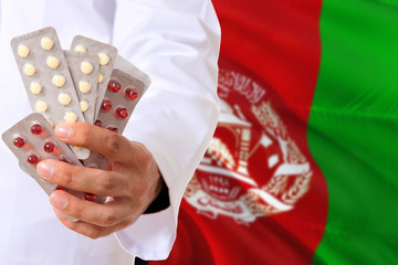 Afghanistan pharmacy and medicine concept. Doctor holding pills tablet on national flag background....