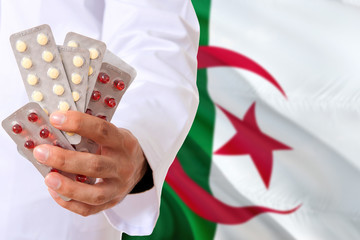 Algeria pharmacy and medicine concept. Doctor holding pills tablet on national flag background....