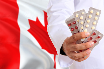 Canada pharmacy and medicine concept. Doctor holding pills tablet on national flag background. Health theme with copy space for text.