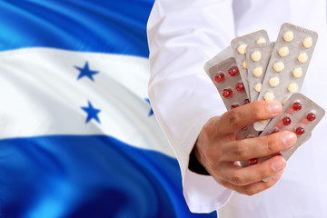Honduras pharmacy and medicine concept. Doctor holding pills tablet on national flag background....