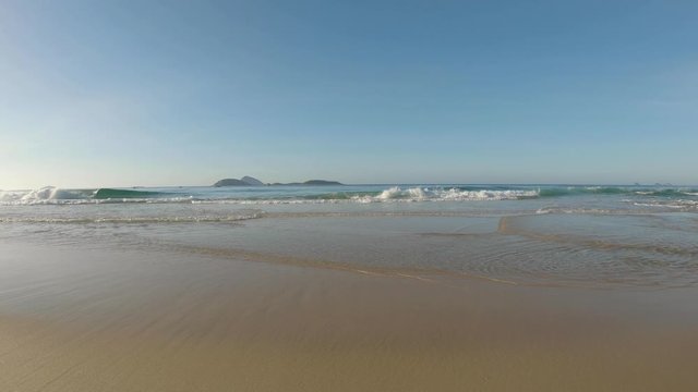 Low angle Atlantic shore seascape with clear water waves coming in at sunrise with the islands just outside of Ipanema beach in Rio de Janeiro on the horizon
