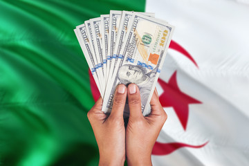 Algeria financial concept. Female hand holding dollar banknotes on national flag background....