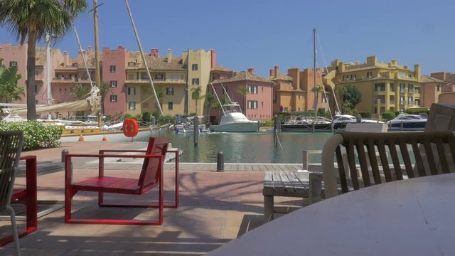 A wide shot of a boat passing by Sotogrande Marina, on a beautiful sunny day in Spain
