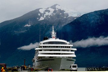 A cruise ship comes into an Alaskan port with snow and glaciers in the background. 