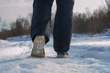 A man walks alone in the park in winter after a snowfall. Walking concept. Rear view of a pedestrian.