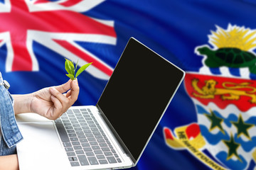 Cayman Islands modern agriculture concept. Farmers holding laptop, check tea on national flag background. Ecology theme with copy space.