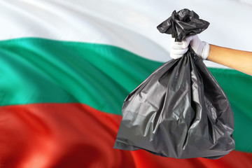 Bulgaria environmental protection concept. The male hand holding a garbage bag on national flag background. Ecological and recycling theme with copy space.