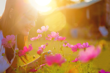 Happiness young woman holding a cosmos flower enjoy with sunlight at sunset..