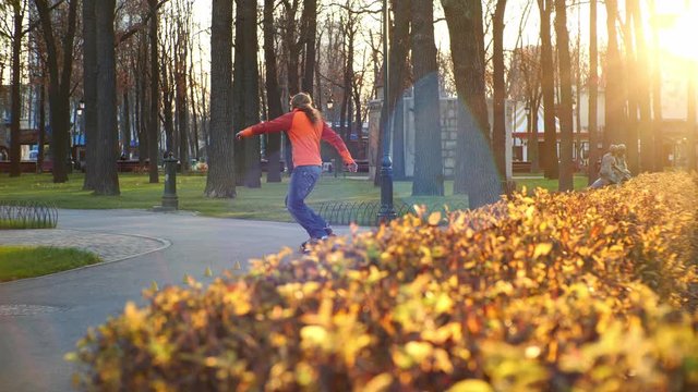A professional male roller blader performs cool tricks and dances on roller skates in a comfortable city park in the last days of autumn. Idea of outdoor activities and a healthy lifestyle in slow