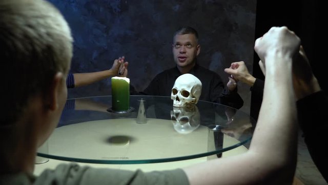 A session of spiritualism group of people sitting at a round table holding hands