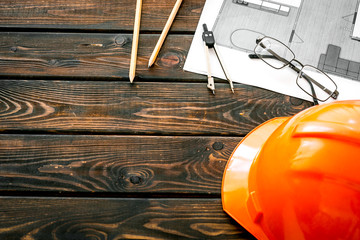 Construction concept. Helmet and blueprints on dark wooden background copy space