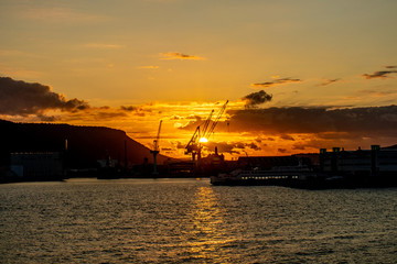 夕暮れに海から望む建設現場のクレーン