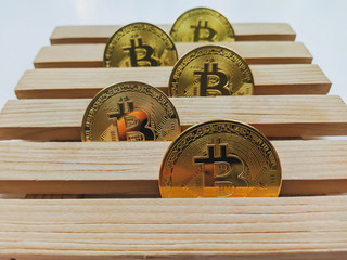 Golden bitcoin coins lined on wooden platform as a concept of investing and collecting...