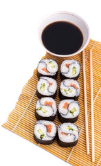 delicious Yin Yang sushi rolls on a Mat with sticks and soy sauce on a white background