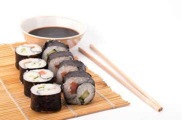 delicious Yin Yang sushi rolls on a Mat with sticks on a white background