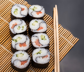 delicious Yin Yang sushi rolls on a Mat with sticks on a black background