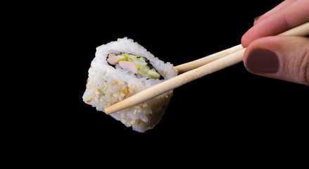 sushi rolls California in sesame on sticks on a black background