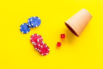 Poker hazard game concept. Chips, dices, cup for dice on yellow background top-down