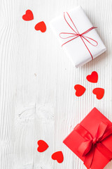 Present to a lover on Valentine's Day. Gift boxes near paper hearts on white wooden background top-down frame copy space