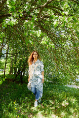Fototapeta na wymiar Girl walking in the park with flowering Apple trees in a spring time