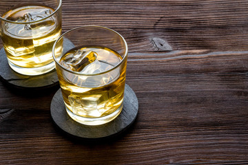 Scotch - two glasses with ice - on dark wooden background copy space