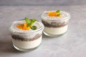 Healthy bowls of yogurt or curd and Chia seeds, topped with chopped oranges and mint leaves. Chia seeds pudding dessert.