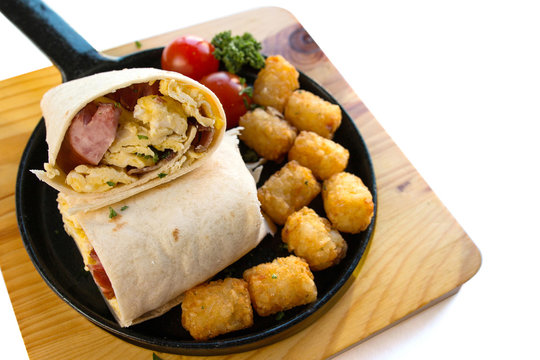 Breakfast Burrito With Sausage And Scrambled Egg And Hash Brown On A Wooden Plate