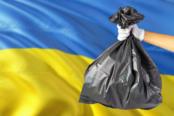 Ukraine environmental protection concept. The male hand holding a garbage bag on national flag background. Ecological and recycling theme with copy space.