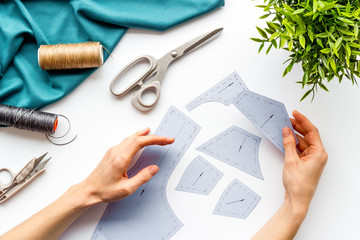 Tailor working. Women hands hold patterns for clothes on white background top-down