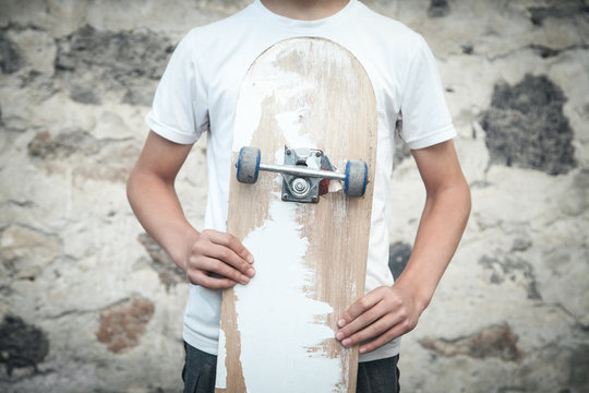 Caucasian boy with skateboard in his hands.