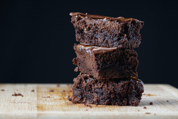 A stack of chocolate brownies on a wooden background. Home made bakery and dessert.