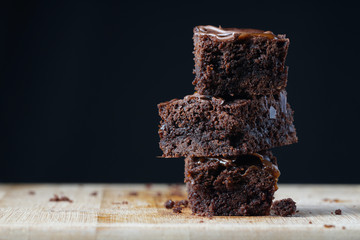 A stack of chocolate brownies on a wooden background. Home made bakery and dessert.