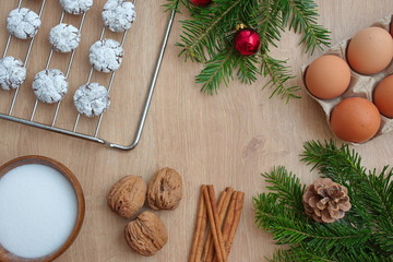 Christmas flat lay with cookies on gridiron, eggs, nuts, cinnamon and pine branch with pine cone